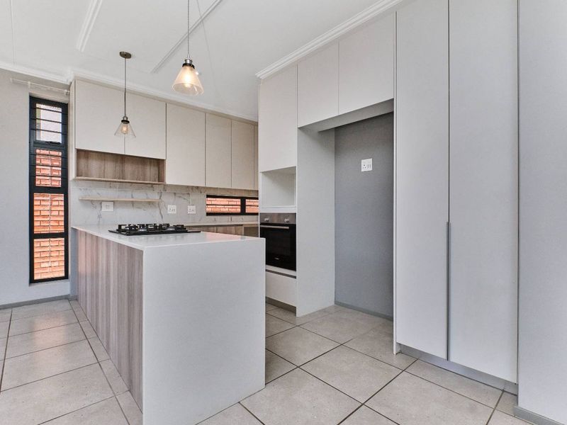 Modern kitchen featuring sleek built-in cabinetry, stone countertops, a gas hob, built-in oven, and a stylish marble-look backsplash with neutral tiled flooring.