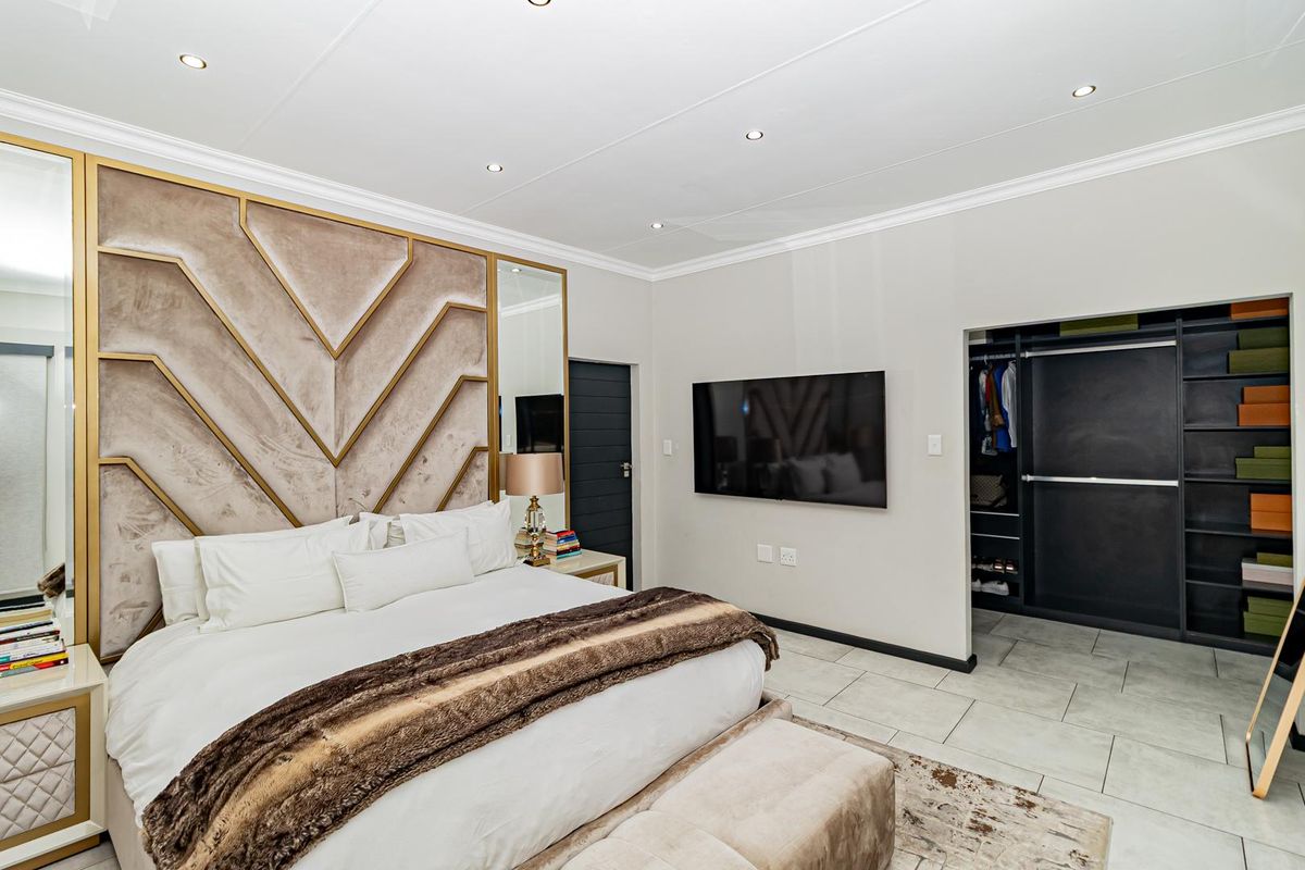 Modern bedroom featuring a custom upholstered headboard, tiled flooring, recessed lighting, and a spacious walk-in closet area.