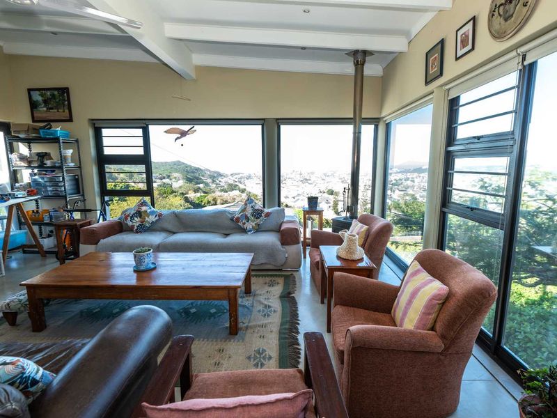 Spacious living room featuring exposed ceiling beams, polished concrete floors, a wood-burning stove, and expansive windows offering panoramic views.