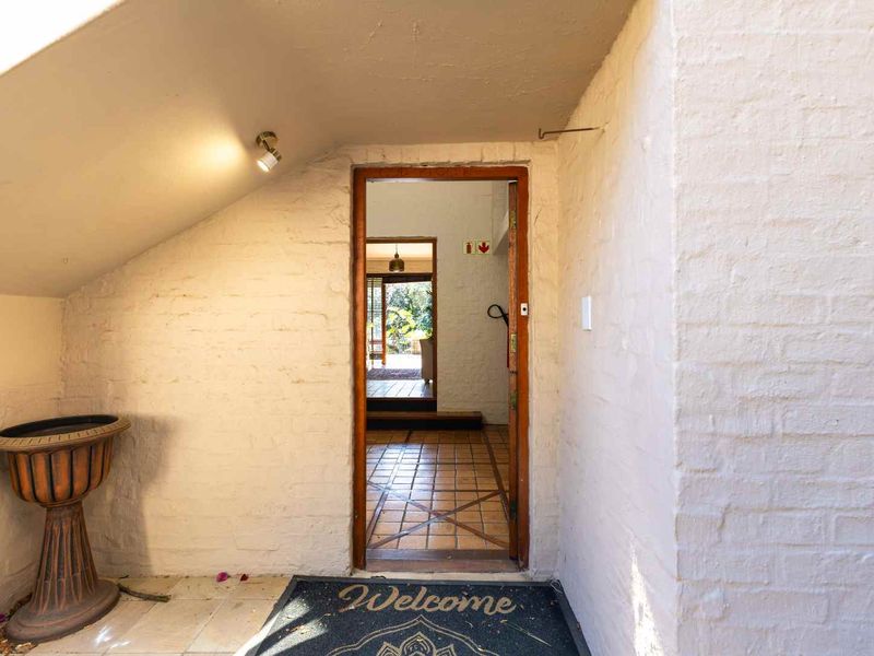 A simple entrance area featuring painted brick walls, tiled flooring, and a sloped ceiling, leading into the main living space of the home.