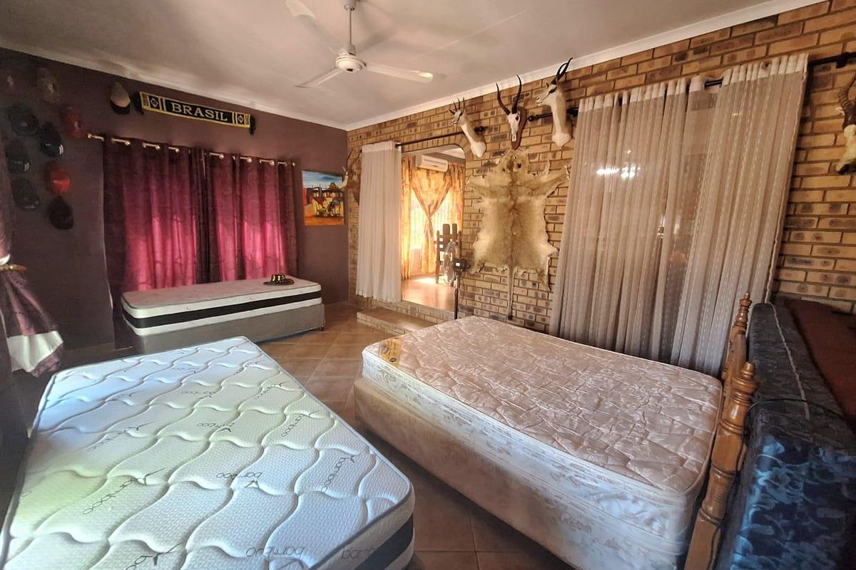 A bedroom featuring exposed brick walls, tiled flooring, and a ceiling fan, with direct access to an adjoining room.