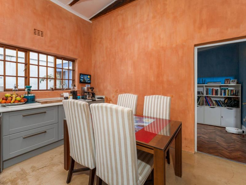A kitchen and dining area featuring grey cabinetry, stone countertops, polished concrete floors, and a distinctive textured orange wall finish.