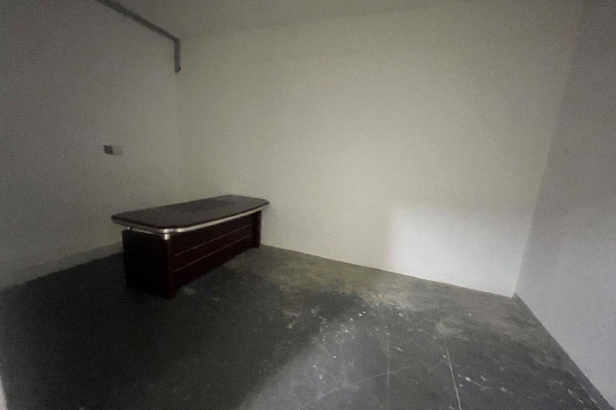 A sparse, unfinished office space featuring bare concrete flooring and exposed wall conduit, suitable for renovation or custom fit-out.