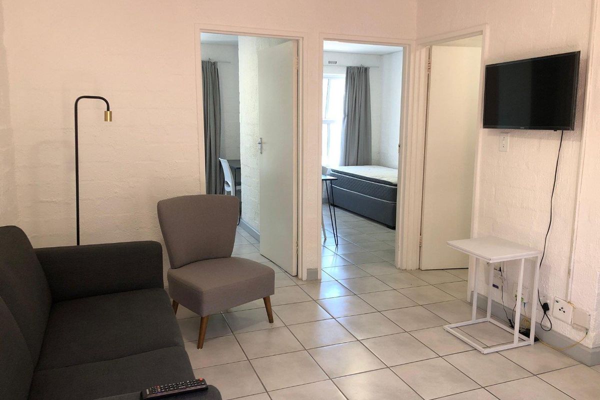 A living area featuring tiled flooring and direct access to adjacent bedrooms, providing a functional and connected layout within the apartment.