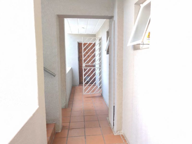 An exterior entrance walkway featuring tiled flooring, a security gate, and an awning window, providing access to the townhouse unit.
