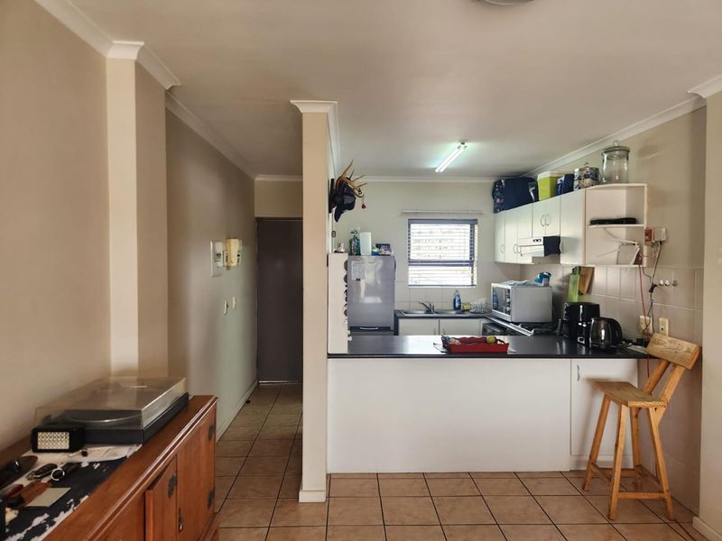 Open plan kitchen area featuring tiled flooring, white cabinetry, and a breakfast bar counter, seamlessly connecting to the adjacent living space.