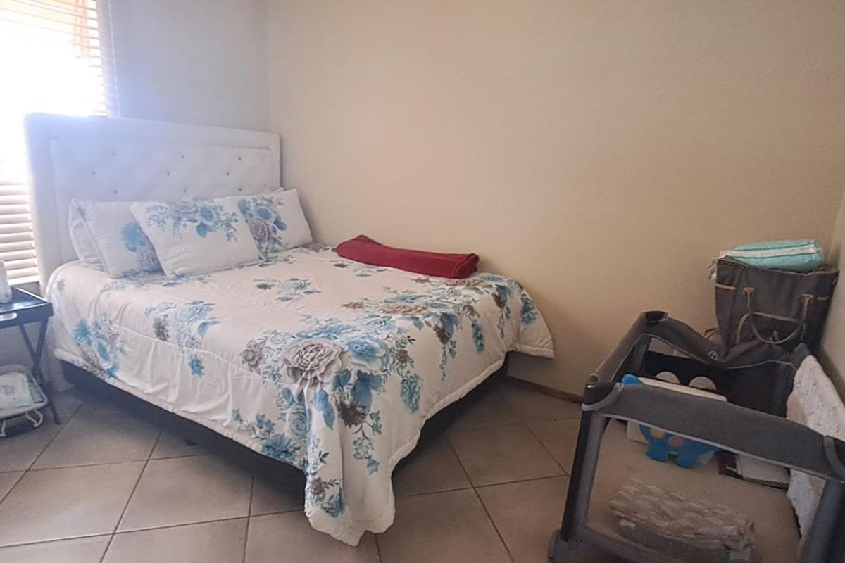 A bedroom featuring tiled flooring and a window with fitted blinds, providing a functional and neutral living space.