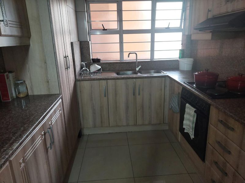 Functional kitchen featuring laminate cabinetry, granite countertops, built-in oven, hob, and extractor fan, with tiled flooring and natural light from the window.