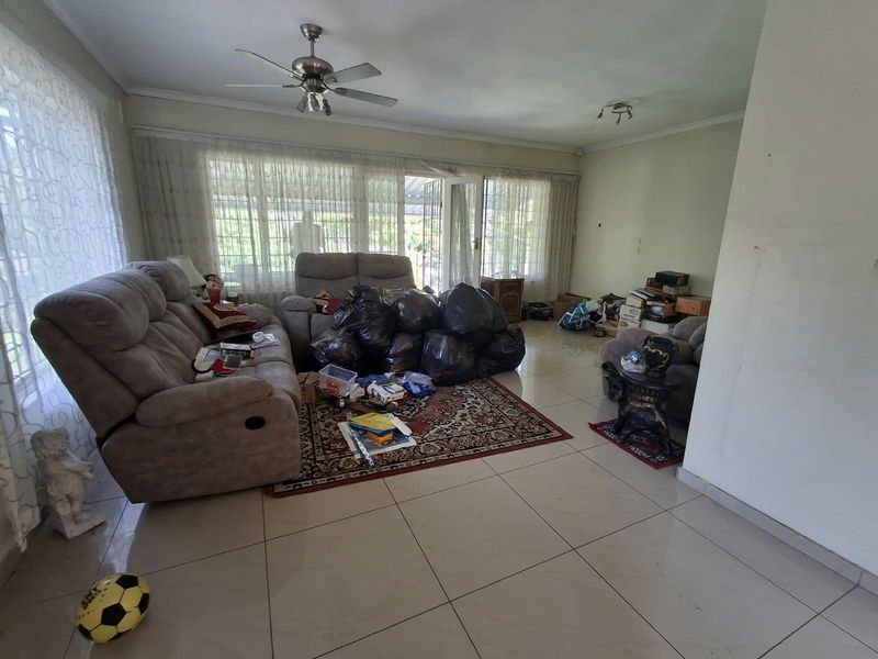 Spacious living room featuring large windows, tiled flooring, and a ceiling fan, offering a bright and open layout with direct access to the outdoors.
