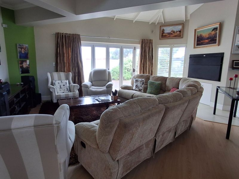 Spacious living room featuring vaulted ceilings, laminate flooring, and large bi-fold doors that provide ample natural light and access to the outdoor area.