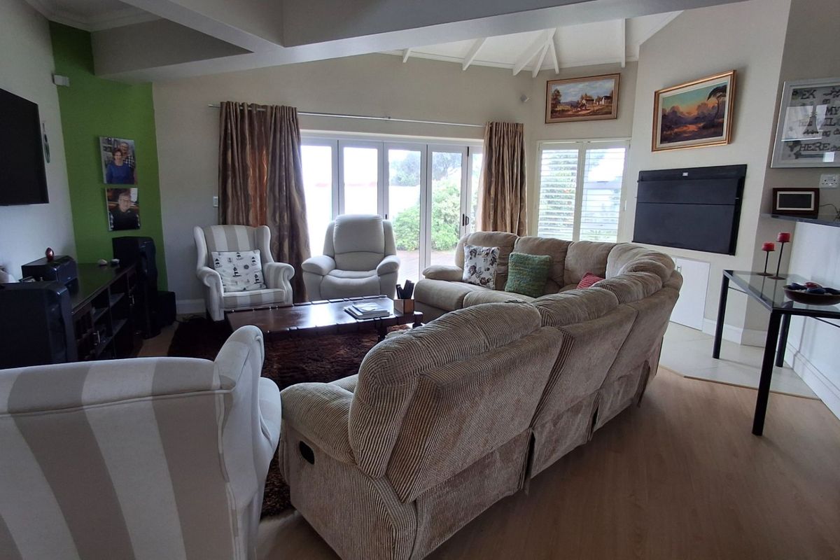 Spacious living room featuring vaulted ceilings, laminate flooring, and large bi-fold doors that provide ample natural light and access to the outdoor area.