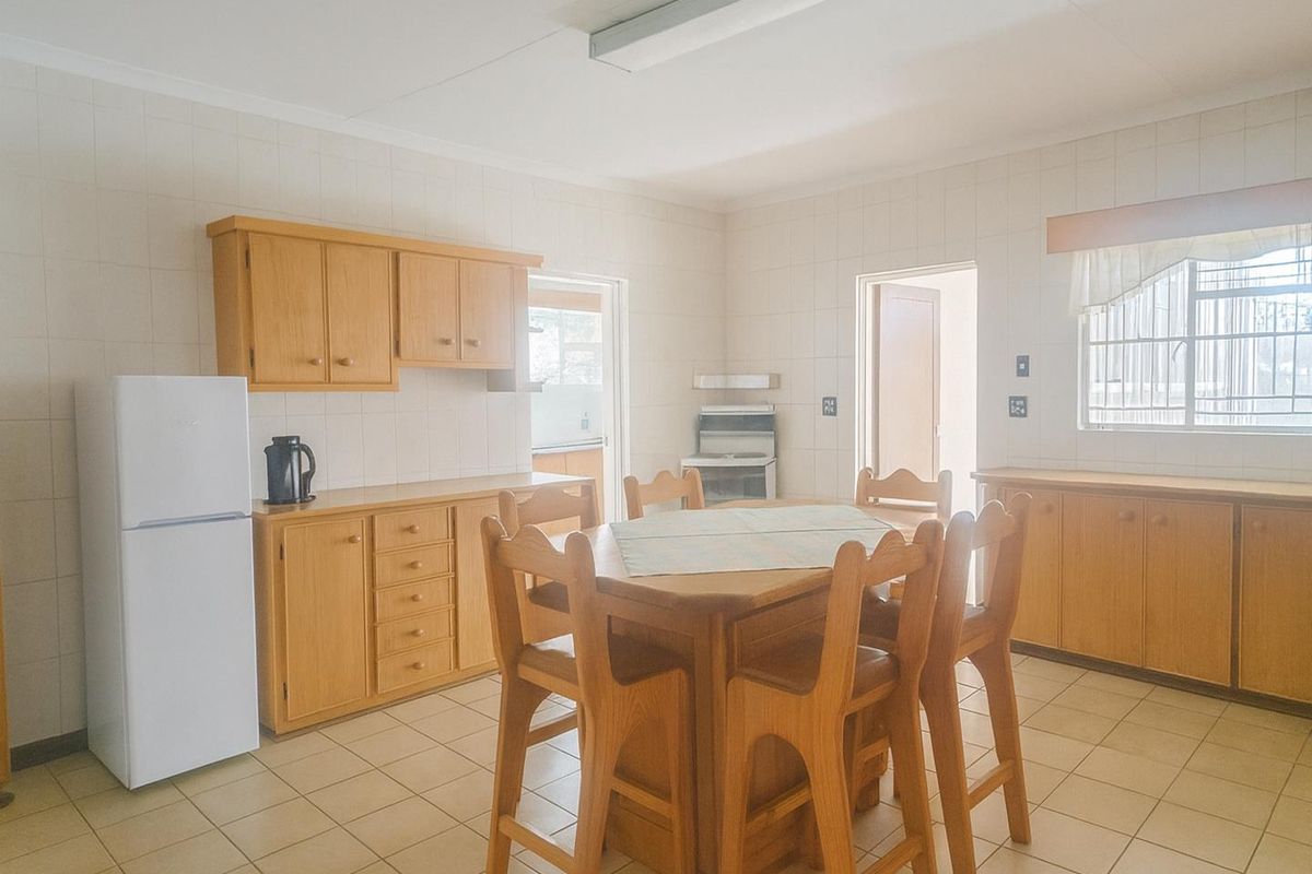 A functional kitchen featuring light wood cabinetry, tiled flooring, and wall-mounted tiles, offering a practical layout with integrated storage and workspace.