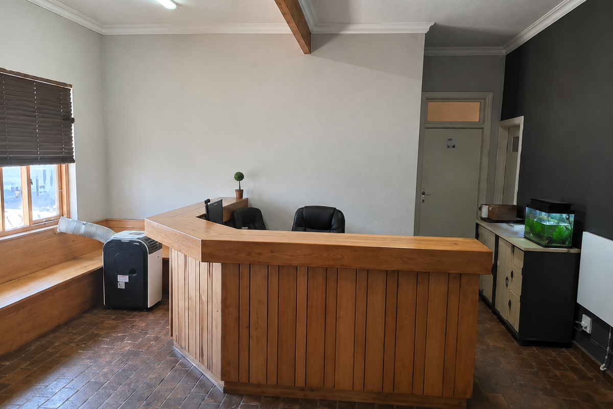 A functional office reception area featuring a large built-in wooden desk, integrated bench seating, and tiled flooring.