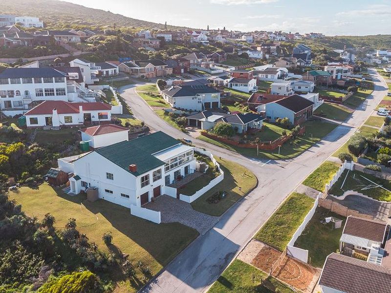 Aerial view of a residential property and surrounding neighbourhood, showcasing the home's position, roof structure, and landscaped grounds.