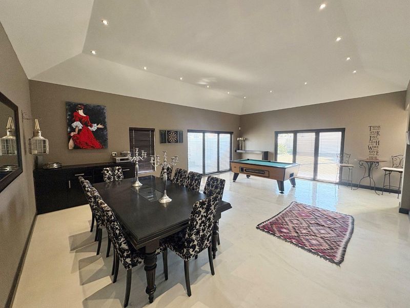 Spacious open-plan living and dining area featuring vaulted ceilings, recessed lighting, polished tiled floors, and large bi-fold doors providing ample natural light.