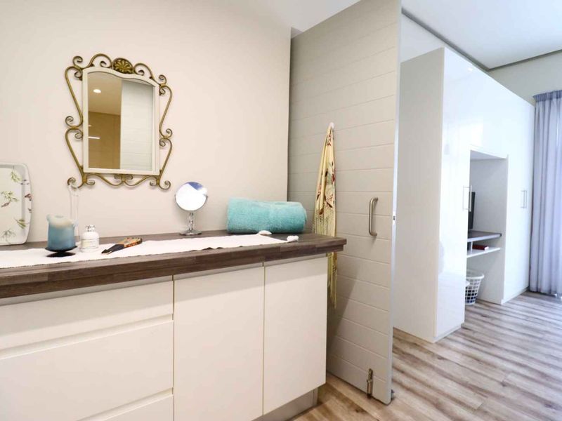 A bedroom featuring modern laminate flooring, built-in cabinetry with a wooden countertop, and a sliding door leading to an adjacent space.