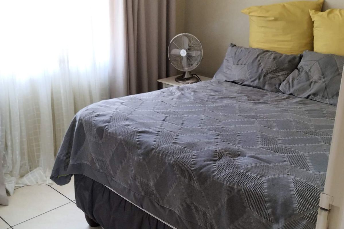 A functional bedroom featuring tiled flooring and natural light from a window with curtains.