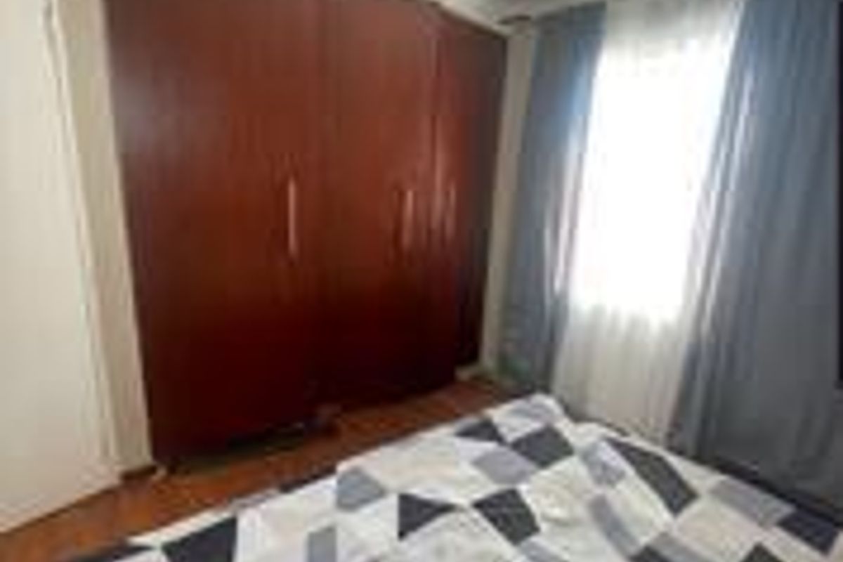A bedroom featuring built-in wooden cupboards and laminate flooring, providing functional storage and a neutral base for interior design.