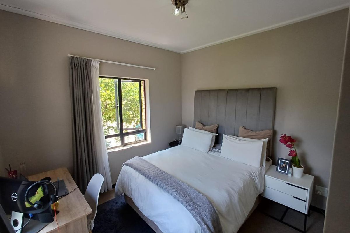 A well-maintained bedroom featuring neutral wall tones, a large window for natural light, and a ceiling-mounted light fixture.