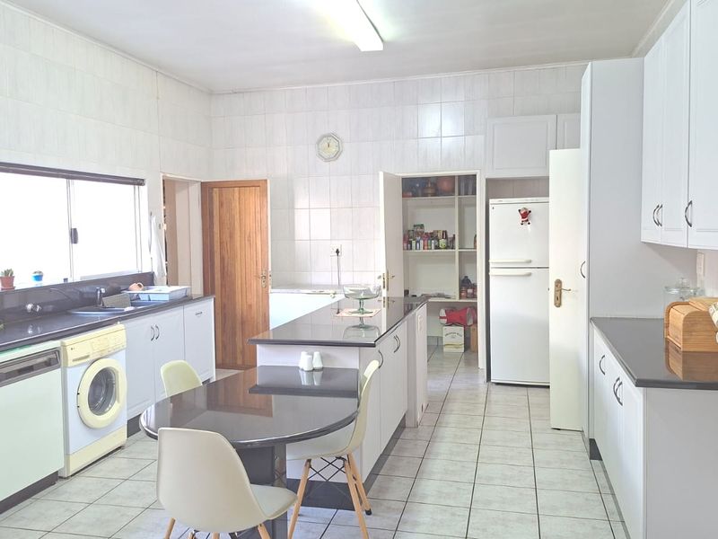 Spacious kitchen featuring granite countertops, built-in appliances, tiled walls, and a dedicated pantry area, offering a functional layout with ample storage.