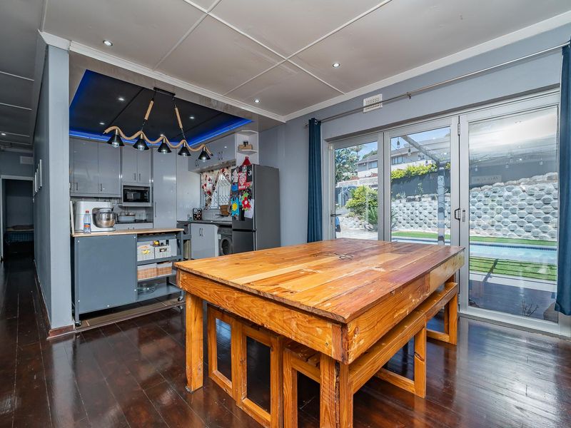 Open plan kitchen and dining area featuring modern cabinetry, recessed lighting, and large sliding glass doors providing direct access to the outdoor pool area.