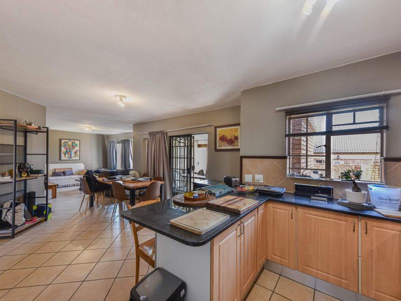 Open-plan kitchen and living area featuring tiled flooring, granite countertops, and light wood cabinetry, with direct access to an outdoor patio area.