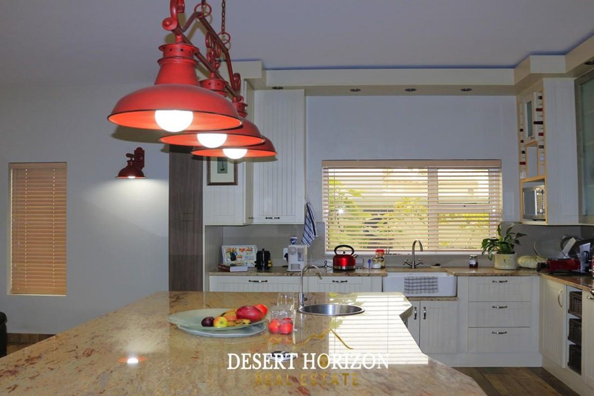 A well-appointed kitchen featuring a large granite island, farmhouse sink, built-in cabinetry, and a gas stove, complemented by stylish pendant lighting.
