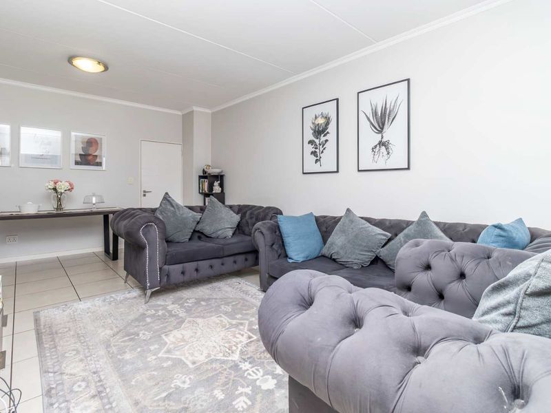 A well-maintained living room featuring neutral tiled flooring and a bright, open layout suitable for comfortable seating arrangements.