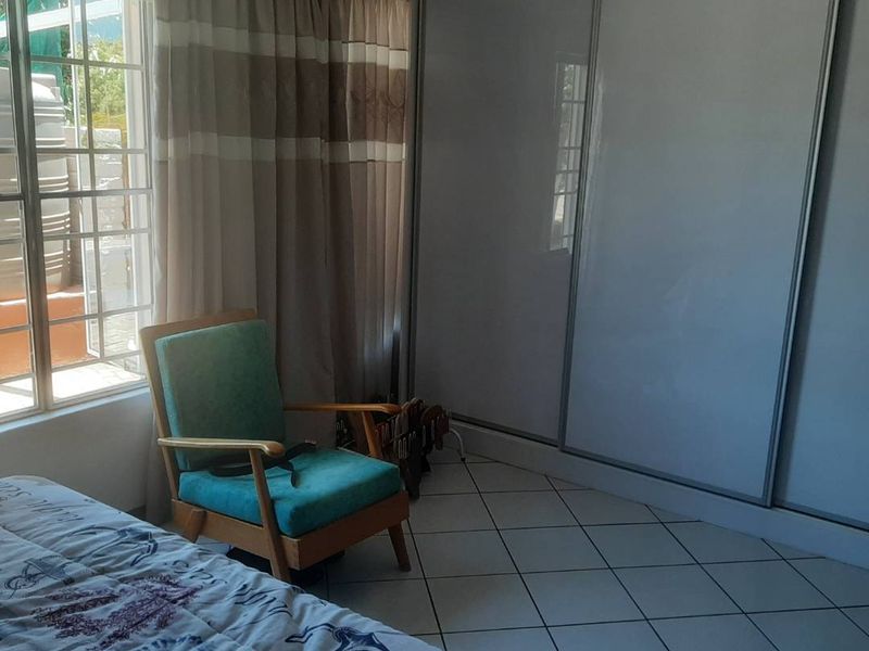 A bedroom featuring tiled flooring and a large built-in sliding door wardrobe, providing ample storage space.