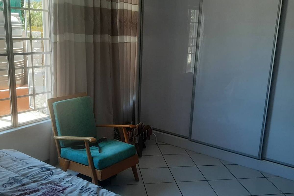 A bedroom featuring tiled flooring and a large built-in sliding door wardrobe, providing ample storage space.