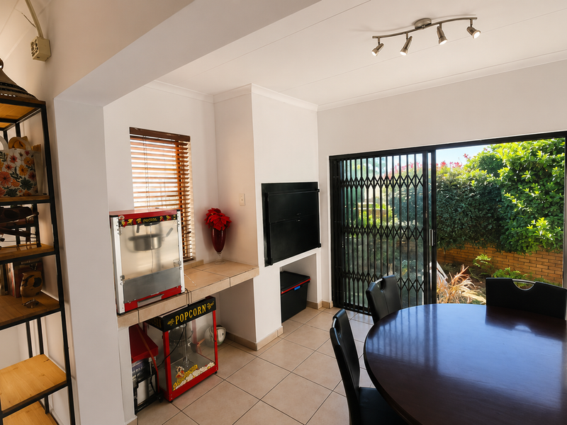 A bright living area featuring a built-in fireplace, tiled flooring, and large sliding doors providing direct access to the garden.