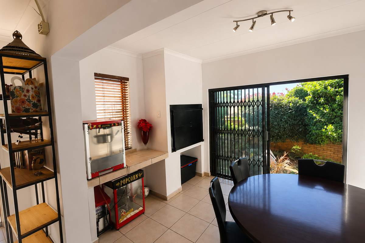 A bright living area featuring a built-in fireplace, tiled flooring, and large sliding doors providing direct access to the garden.