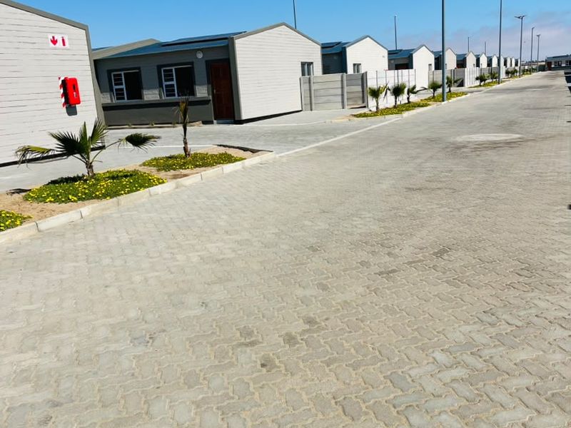 A view of a modern townhouse complex featuring paved driveways, uniform exterior facades, and street lighting.