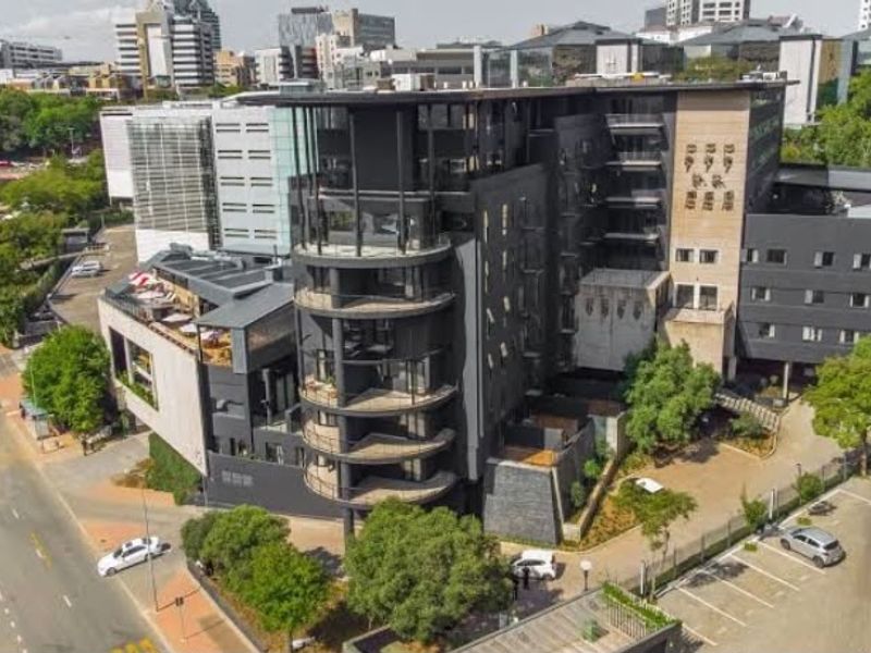 Aerial view of a modern multi-story apartment complex featuring contemporary architecture, private balconies, and integrated parking facilities in an urban setting.