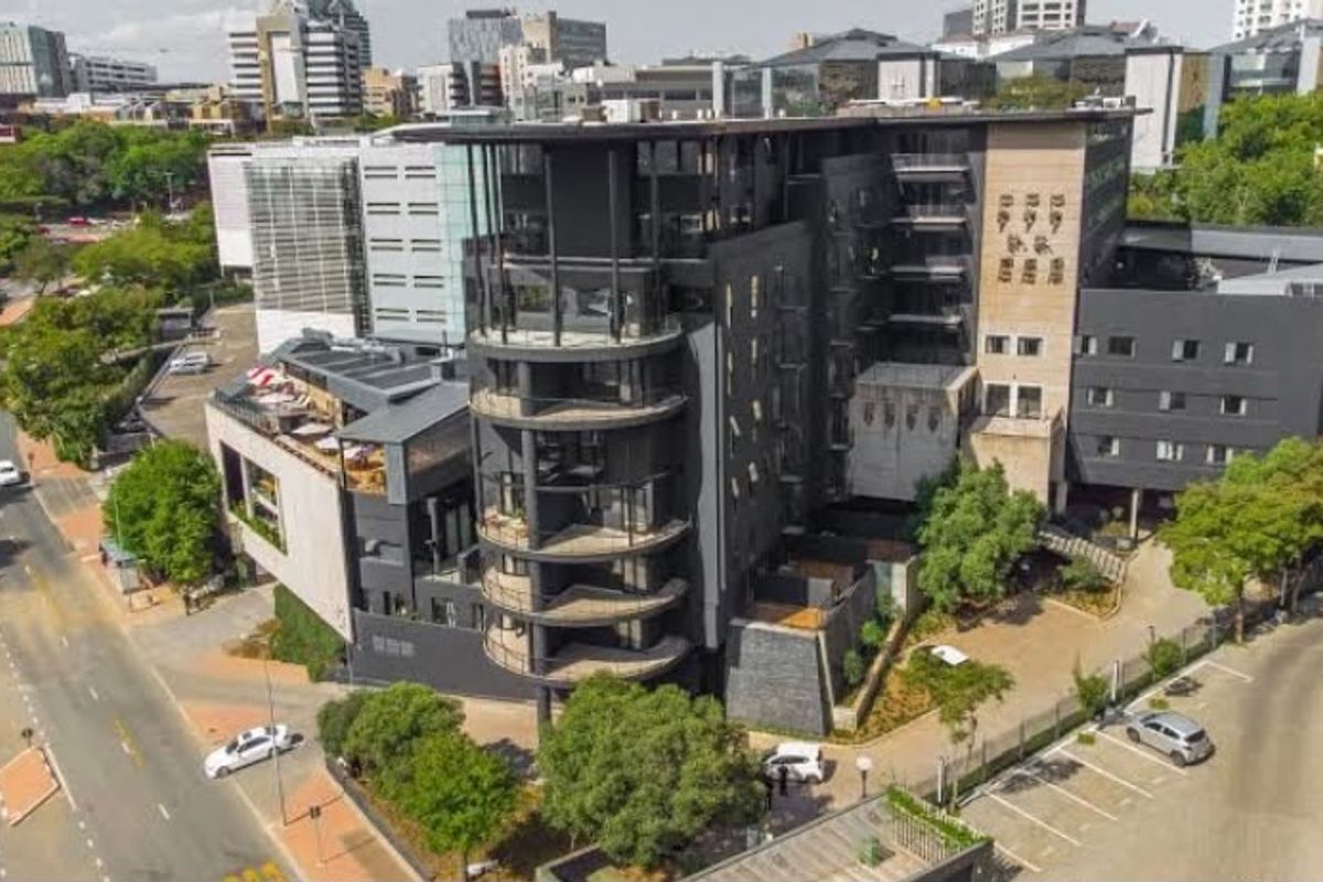 Aerial view of a modern multi-story apartment complex featuring contemporary architecture, private balconies, and integrated parking facilities in an urban setting.