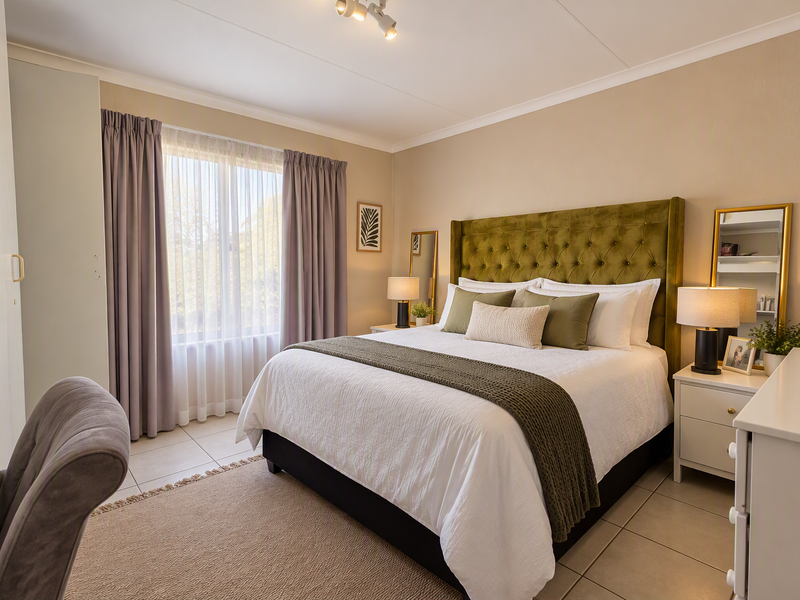 A well-maintained bedroom featuring neutral tiled flooring, built-in wardrobe storage, and large windows with curtain tracks, offering a bright and comfortable living space.