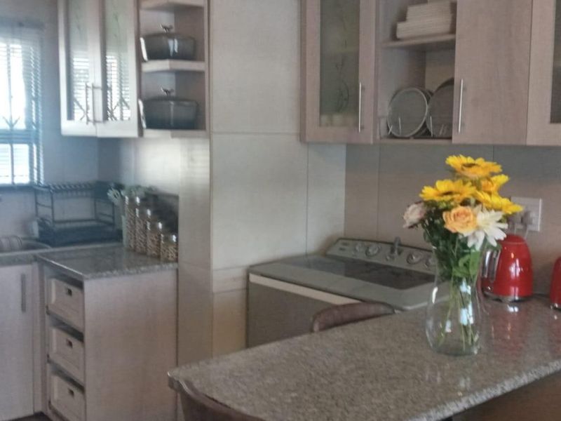 A functional kitchen featuring granite countertops, ample built-in cabinetry, and a stainless steel sink with a window overlooking the exterior.