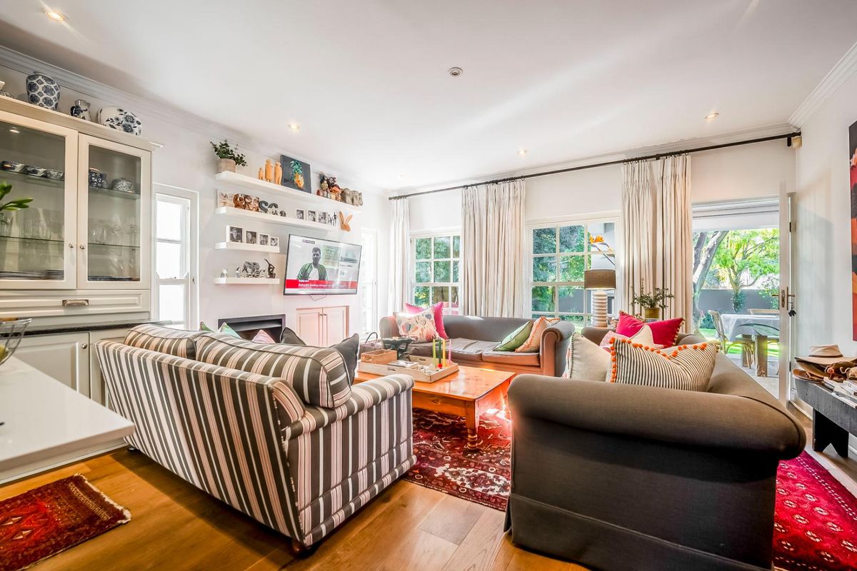 A bright and inviting living room featuring hardwood floors, built-in cabinetry, a fireplace, and direct access to the garden through french doors.