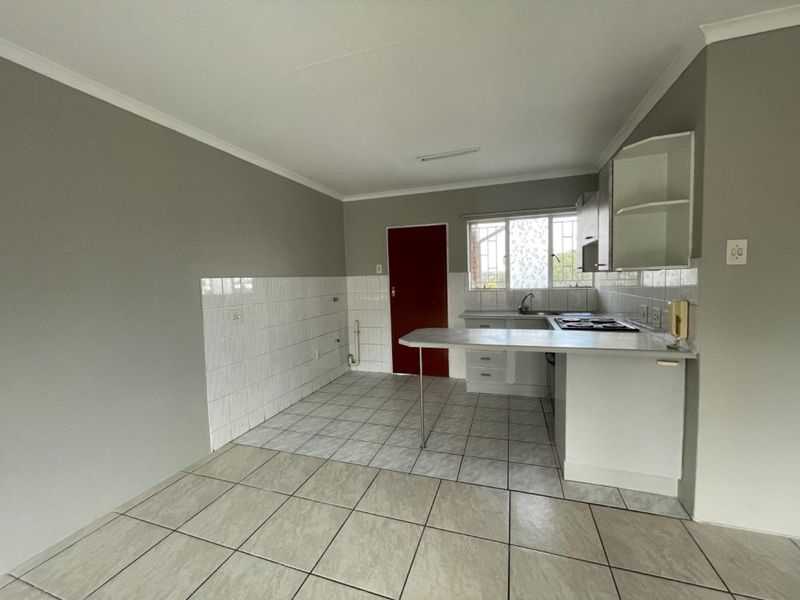 A functional kitchen featuring built-in cabinetry, a breakfast counter, tiled backsplash, and tiled flooring, offering a clean and practical layout.