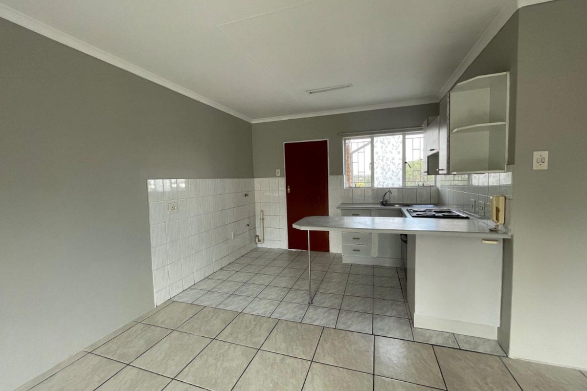 A functional kitchen featuring built-in cabinetry, a breakfast counter, tiled backsplash, and tiled flooring, offering a clean and practical layout.