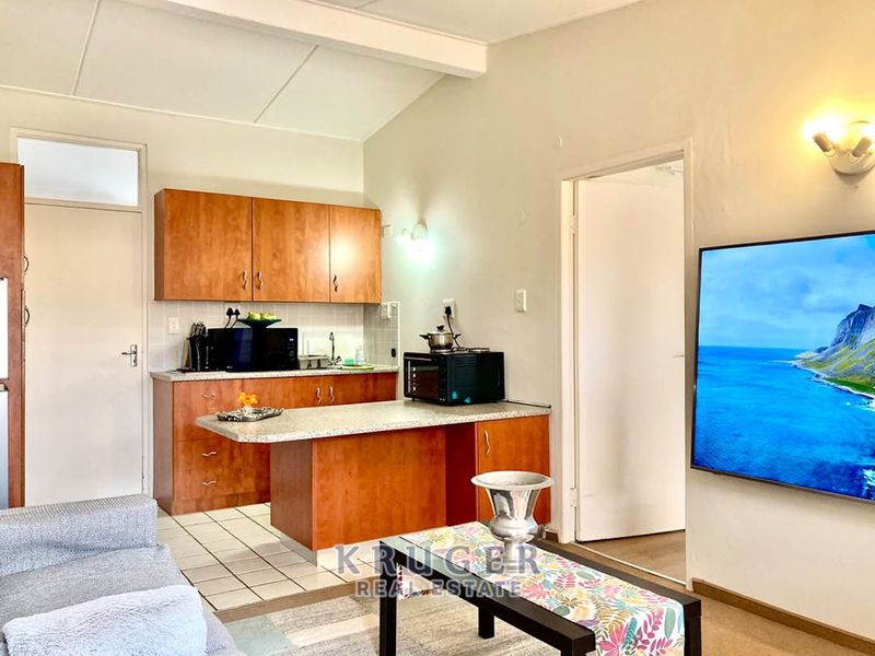 Open-plan living area featuring a functional kitchen with laminate cabinetry and a breakfast bar, seamlessly connecting to the adjacent living space.