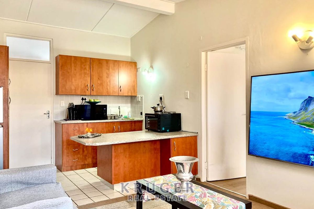 Open-plan living area featuring a functional kitchen with laminate cabinetry and a breakfast bar, seamlessly connecting to the adjacent living space.