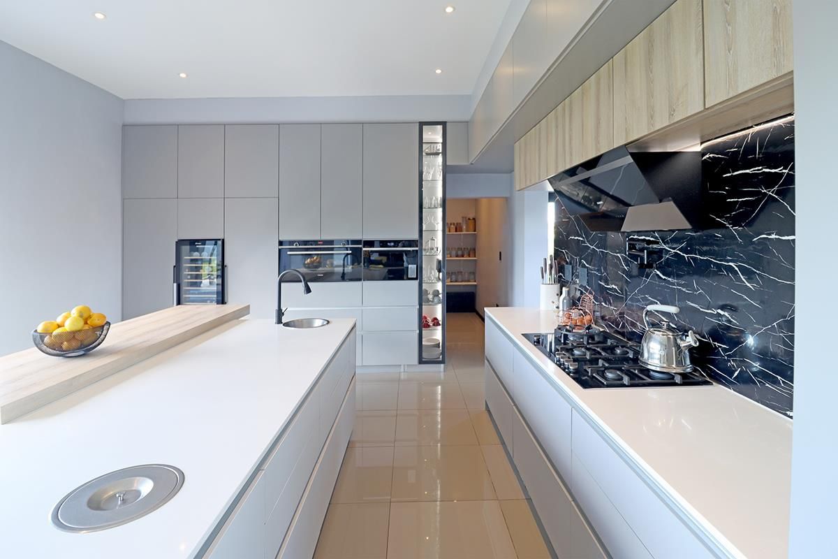 Modern kitchen featuring sleek grey cabinetry, a large central island with a prep sink, integrated appliances, and a striking black marble-look splashback.
