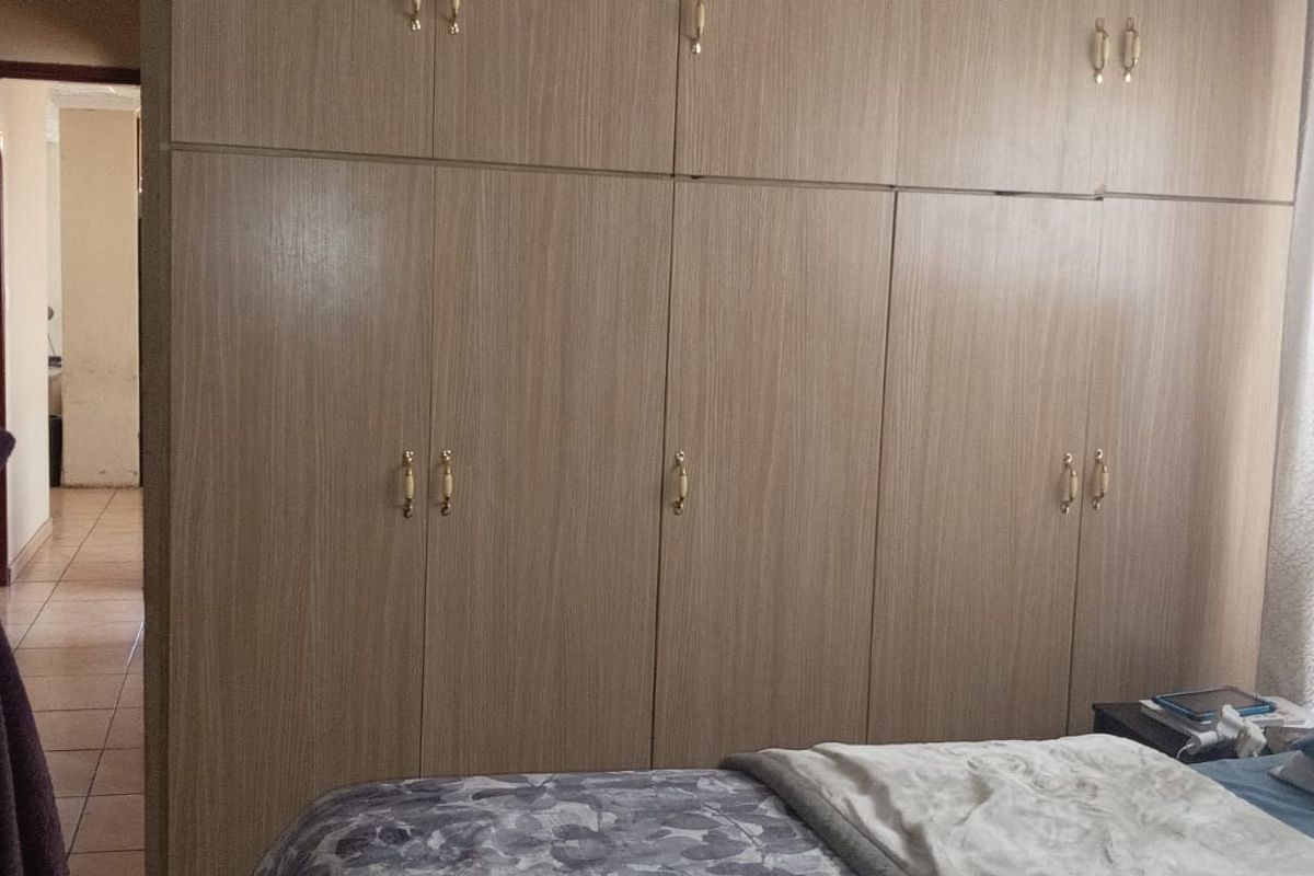 A bedroom featuring extensive built-in wooden cabinetry with overhead storage, providing ample integrated storage space.