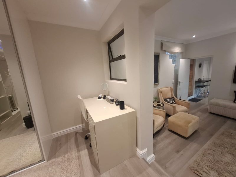An open-plan living area featuring modern laminate flooring, recessed lighting, and a built-in wardrobe, creating a bright and functional space.