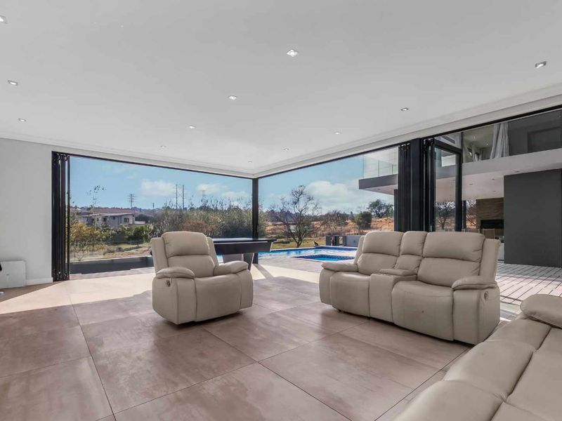 Spacious modern living area featuring large format floor tiles, recessed lighting, and expansive bi-fold glass doors opening directly to the swimming pool and outdoor area.