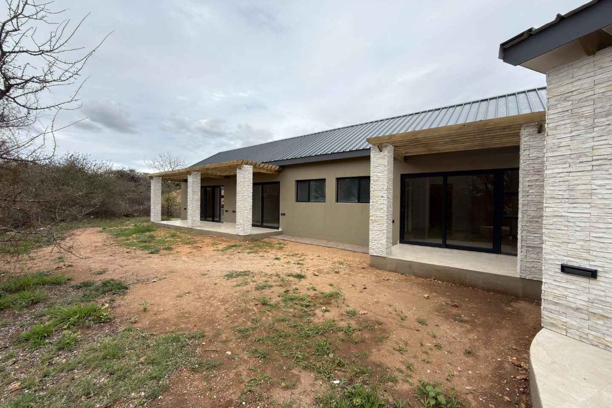 Rear view of the property featuring a covered patio with timber pergola, stone cladding accents, and modern sliding glass doors leading to the garden.