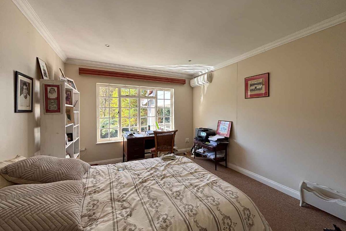 A bedroom featuring a large window with natural light, crown molding, and a wall-mounted air conditioning unit.