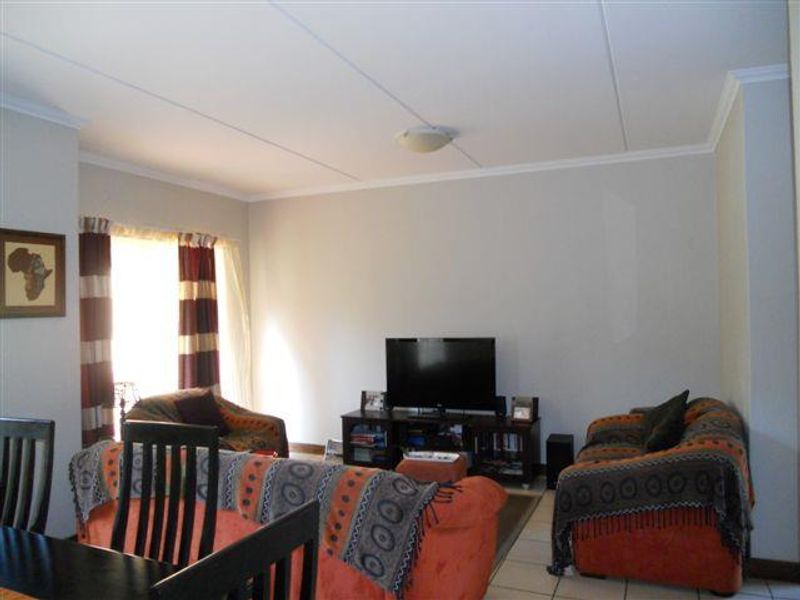 A comfortable living room featuring tiled flooring and a coved ceiling, providing a functional and neutral space for relaxation.