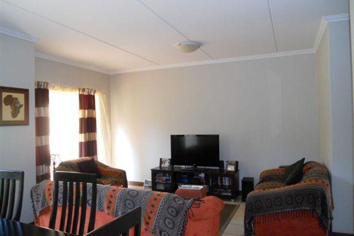A comfortable living room featuring tiled flooring and a coved ceiling, providing a functional and neutral space for relaxation.